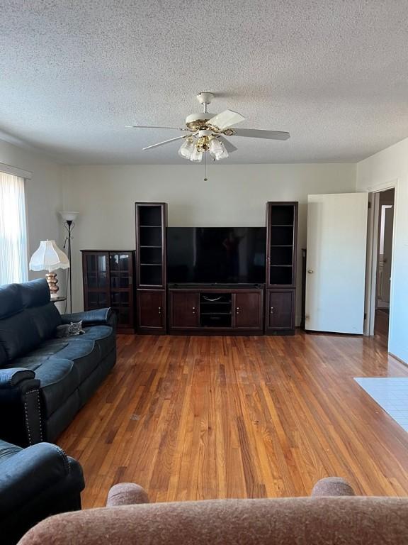 living room featuring ceiling fan, hardwood / wood-style floors, and a textured ceiling