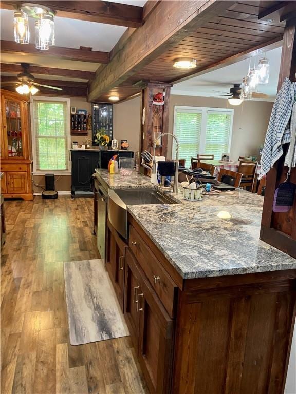 kitchen with ceiling fan, beam ceiling, light stone countertops, and light hardwood / wood-style flooring