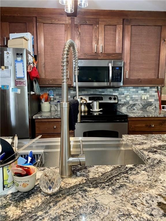 kitchen featuring stainless steel appliances, stone counters, and backsplash