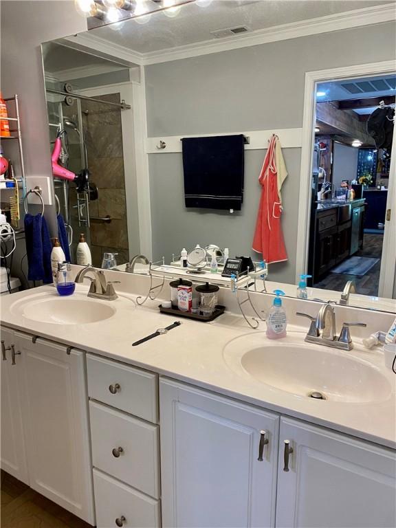 bathroom with ornamental molding, vanity, and walk in shower