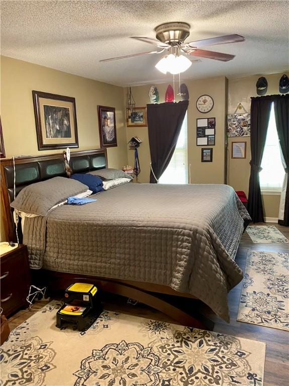 bedroom with wood-type flooring, a textured ceiling, and ceiling fan