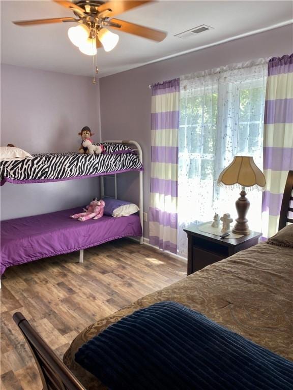 bedroom with multiple windows, hardwood / wood-style floors, and ceiling fan