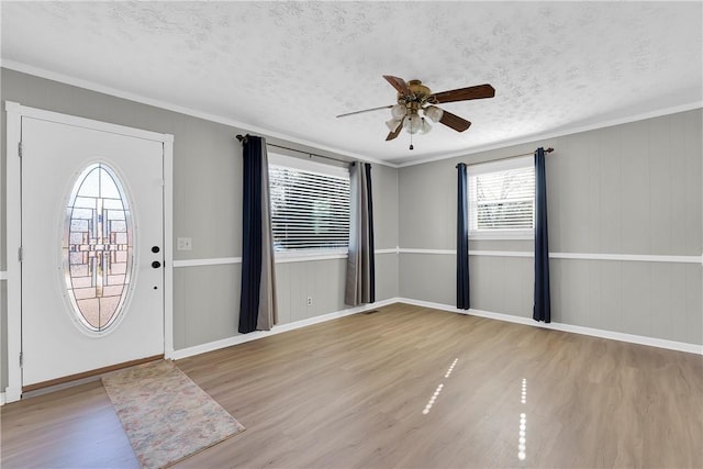 foyer entrance featuring ceiling fan, ornamental molding, light hardwood / wood-style floors, and a textured ceiling