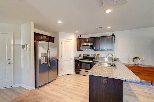 kitchen featuring sink, appliances with stainless steel finishes, dark brown cabinets, light hardwood / wood-style floors, and kitchen peninsula