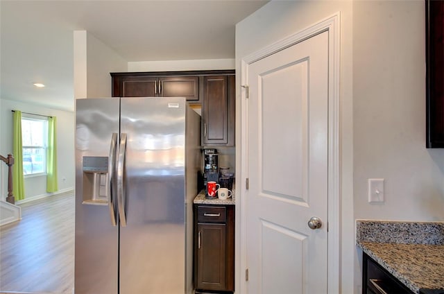 kitchen with light stone counters, dark brown cabinetry, stainless steel fridge, and light hardwood / wood-style floors