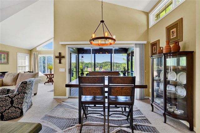 dining area with light carpet, high vaulted ceiling, and an inviting chandelier