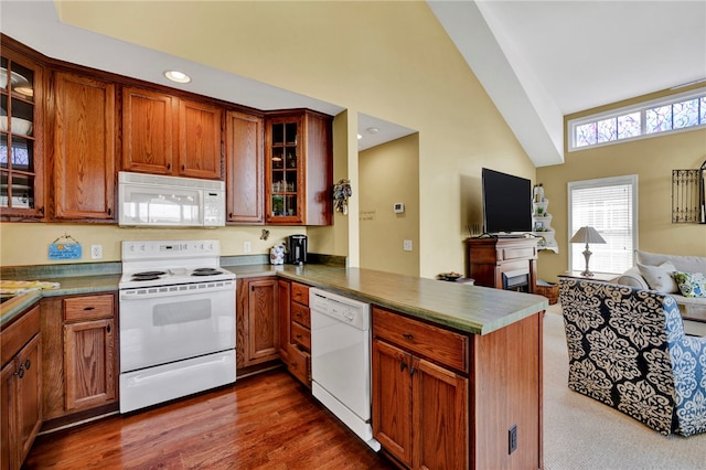 kitchen featuring dark hardwood / wood-style flooring, vaulted ceiling, white appliances, and kitchen peninsula