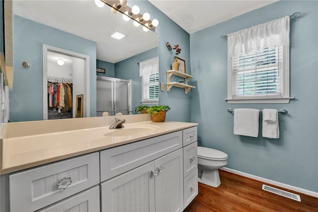 bathroom with wood-type flooring, toilet, an enclosed shower, and vanity