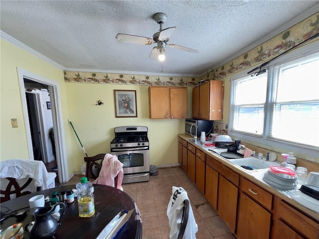 kitchen with sink, ceiling fan, a textured ceiling, and appliances with stainless steel finishes