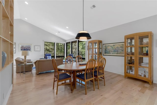 dining area with high vaulted ceiling and light wood-type flooring