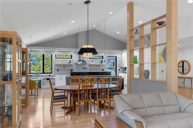 dining space featuring high vaulted ceiling and light wood-type flooring