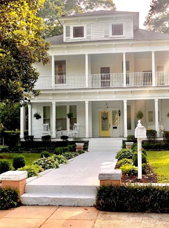 farmhouse inspired home with a porch and a balcony