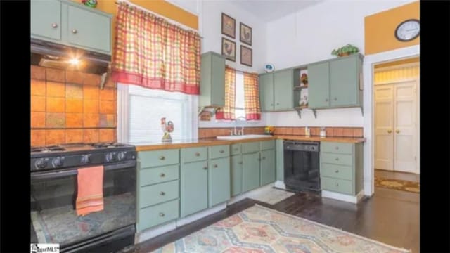 kitchen featuring range hood, sink, black dishwasher, range, and green cabinetry