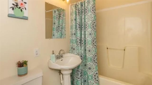 bathroom featuring shower / bathtub combination with curtain and toilet