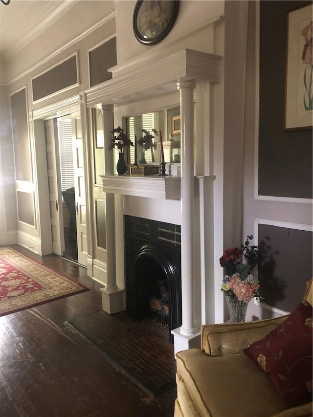 living room with ornate columns, a tiled fireplace, and dark hardwood / wood-style flooring