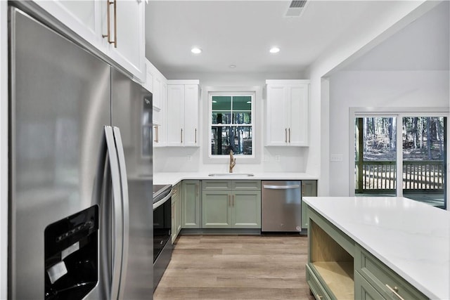 kitchen with white cabinetry, green cabinetry, stainless steel appliances, and sink