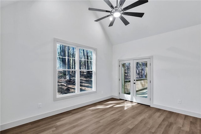 empty room featuring hardwood / wood-style flooring, high vaulted ceiling, french doors, and ceiling fan