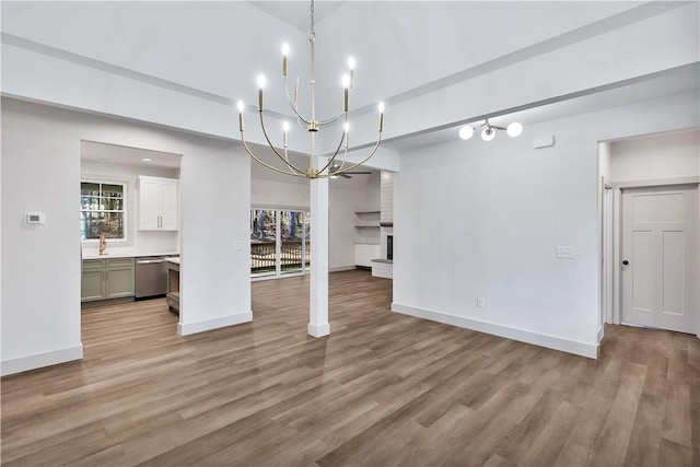 unfurnished dining area featuring sink, a large fireplace, a chandelier, and light wood-type flooring