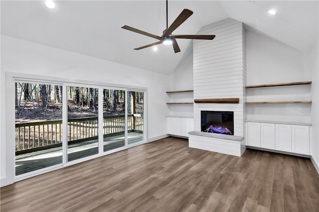 unfurnished living room with ceiling fan, high vaulted ceiling, a large fireplace, and dark hardwood / wood-style floors