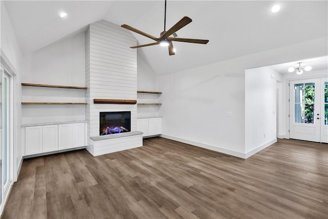 unfurnished living room with dark hardwood / wood-style flooring, high vaulted ceiling, a large fireplace, and ceiling fan