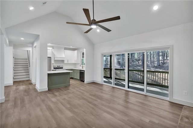 unfurnished living room featuring high vaulted ceiling, light hardwood / wood-style floors, sink, and ceiling fan