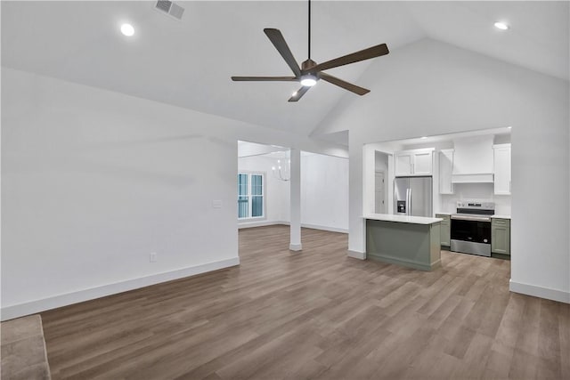 unfurnished living room featuring high vaulted ceiling, ceiling fan with notable chandelier, and light hardwood / wood-style floors