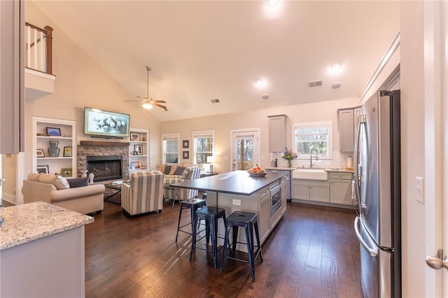 kitchen featuring a stone fireplace, a breakfast bar, sink, a center island, and stainless steel appliances