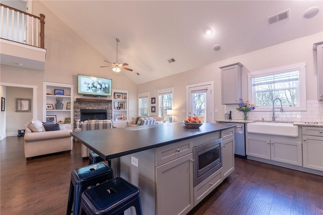 kitchen with a kitchen island, stainless steel microwave, a fireplace, sink, and dark hardwood / wood-style flooring