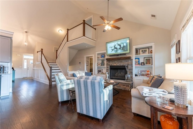 living room with built in shelves, a fireplace, dark hardwood / wood-style floors, and ceiling fan