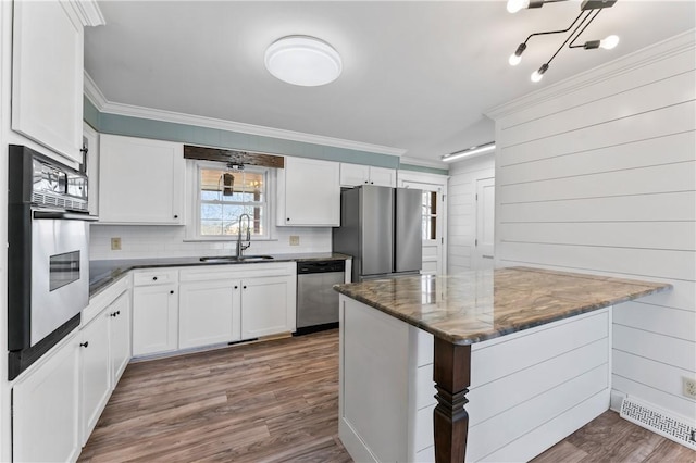 kitchen with stainless steel appliances, white cabinetry, sink, and crown molding