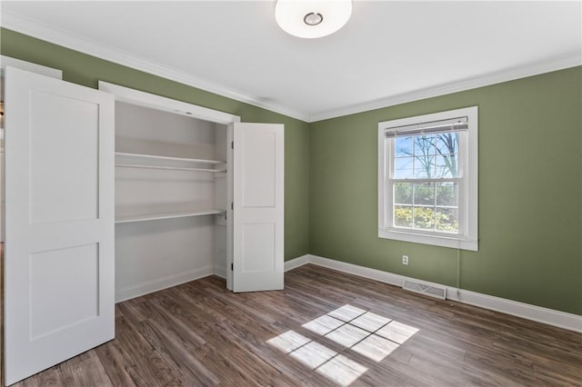 unfurnished bedroom featuring crown molding, dark wood-type flooring, and a closet