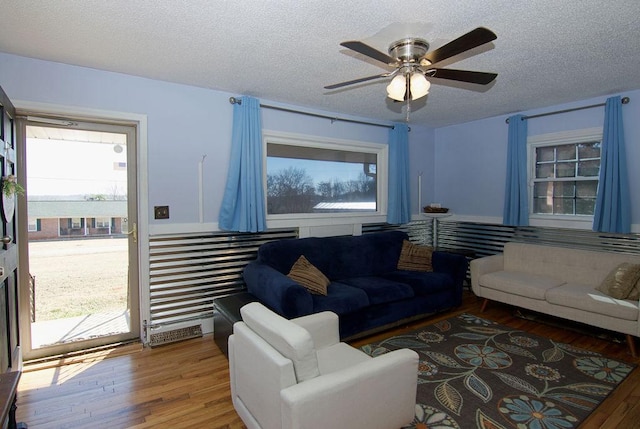 living room featuring ceiling fan, hardwood / wood-style floors, and a textured ceiling