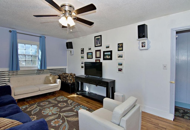 living room featuring ceiling fan, dark hardwood / wood-style floors, and a textured ceiling