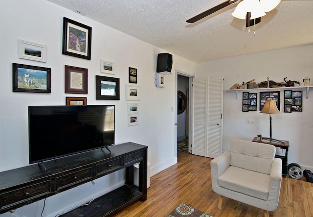 living room featuring ceiling fan, a textured ceiling, and light hardwood / wood-style flooring