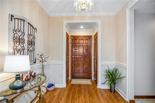 entryway featuring crown molding, light hardwood / wood-style flooring, and a notable chandelier