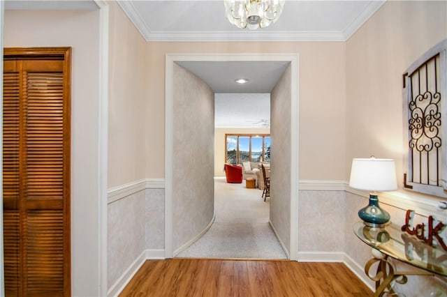 hall featuring ornamental molding, light hardwood / wood-style flooring, and a notable chandelier