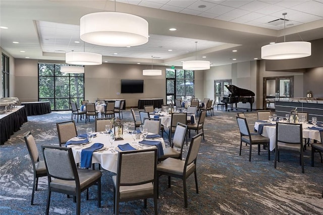 dining area featuring a raised ceiling, a towering ceiling, and dark carpet