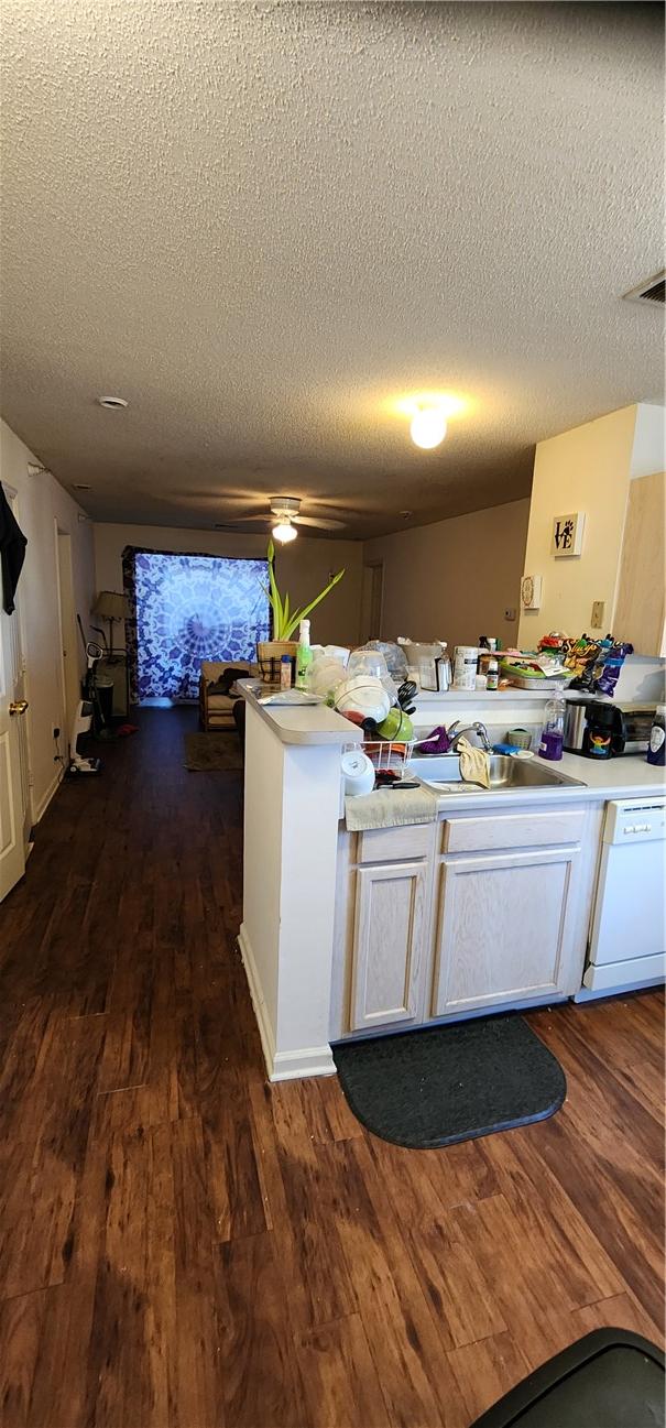 kitchen with dark hardwood / wood-style flooring, sink, white dishwasher, and kitchen peninsula