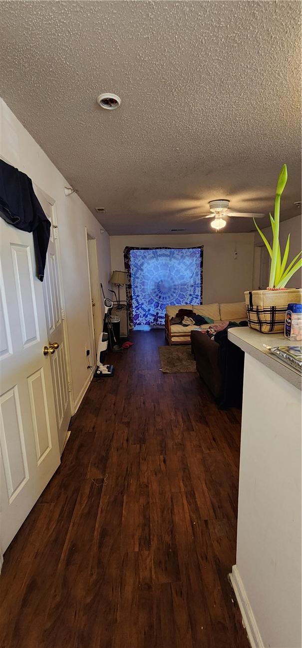 hallway featuring dark wood-type flooring and a textured ceiling