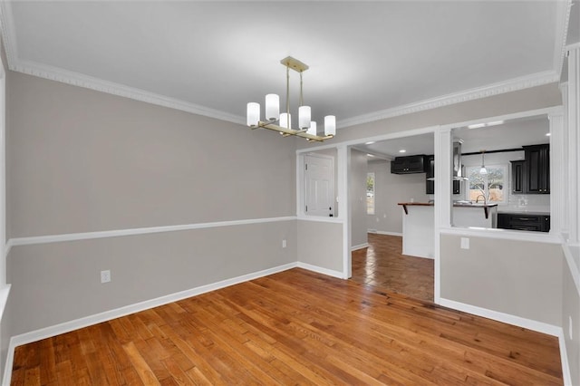 unfurnished dining area with hardwood / wood-style flooring, crown molding, and a chandelier