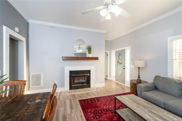 living room featuring crown molding, wood-type flooring, and ceiling fan