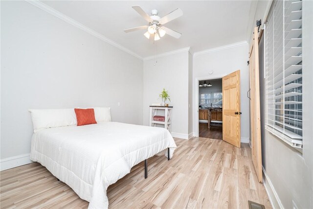 bedroom with crown molding, a barn door, ceiling fan, and light wood-type flooring