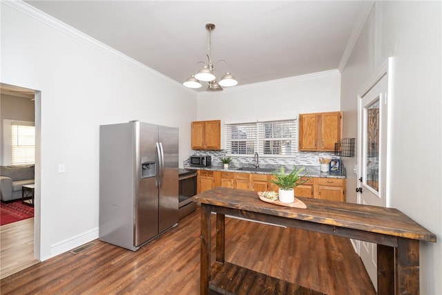 kitchen with decorative light fixtures, ornamental molding, appliances with stainless steel finishes, dark hardwood / wood-style flooring, and decorative backsplash