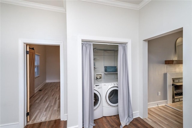 clothes washing area with separate washer and dryer, dark wood-type flooring, and ornamental molding