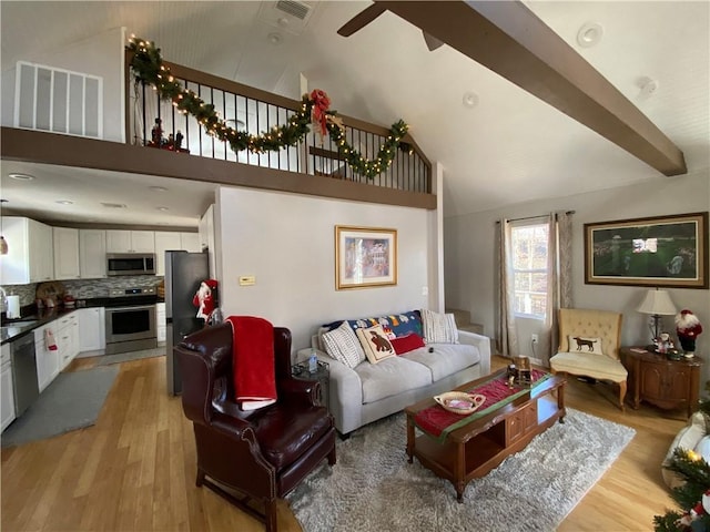 living room with beamed ceiling, high vaulted ceiling, and light wood-type flooring