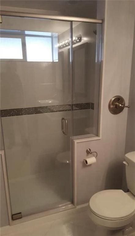 bathroom with a shower with door and toilet