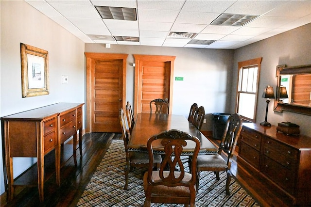 dining room with a drop ceiling and dark hardwood / wood-style floors