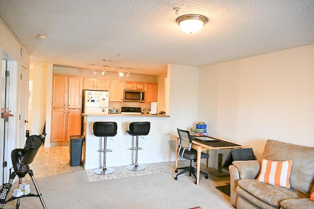 kitchen featuring light carpet, a textured ceiling, white refrigerator, a kitchen breakfast bar, and kitchen peninsula