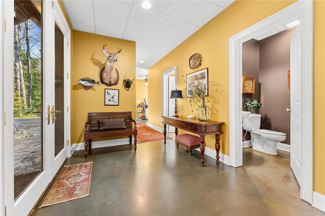 hallway with plenty of natural light, a paneled ceiling, and french doors