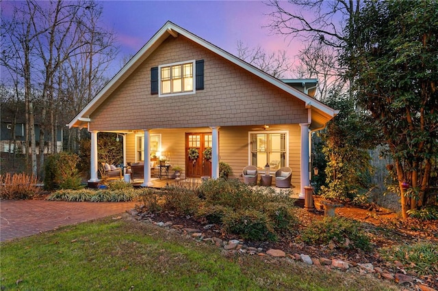 back house at dusk featuring a porch